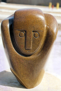 Shona stone sculpture with a smooth rounded form and a stylized human face carved into warm brown stone. Featured on a page about Shona sculpture and African art.